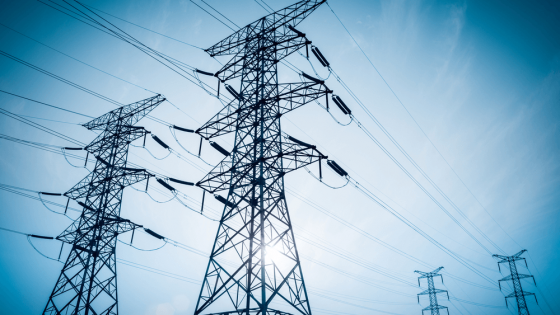 electricity transmission pylon silhouetted against blue sky at dusk