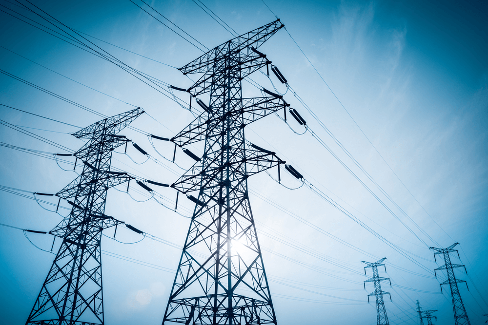 electricity transmission pylon silhouetted against blue sky at dusk